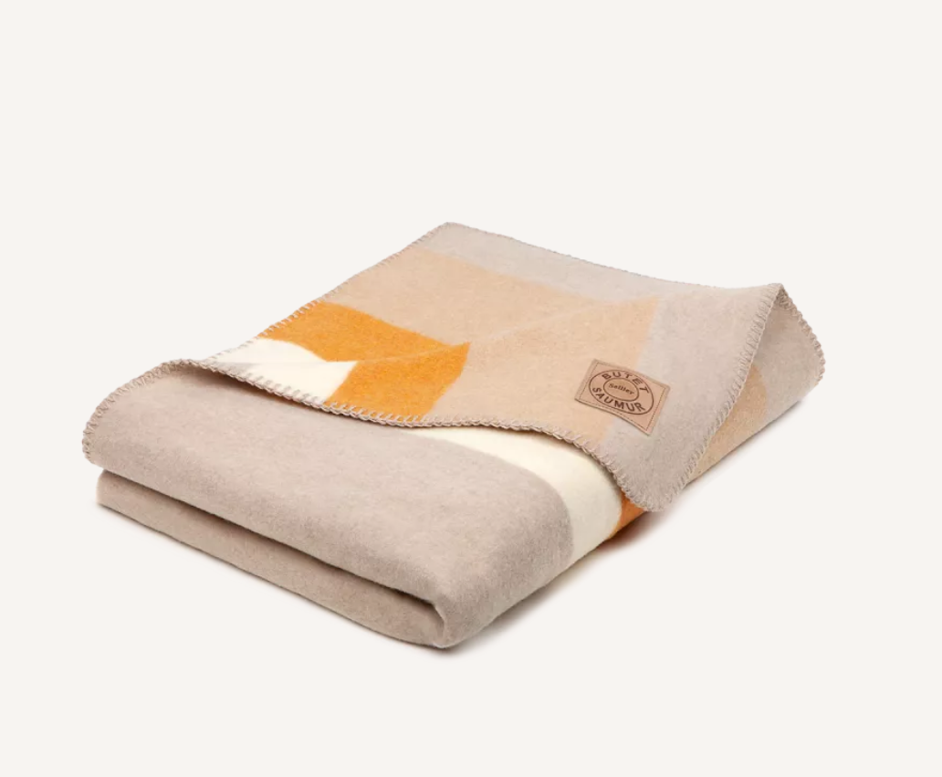 Tan and yellow wool blanket is folded on a white background