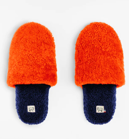 Orange and navy blue fuzzy slippers on white background.