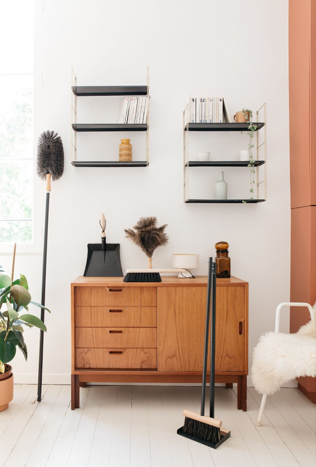 Minimalist room with furniture, shelves, extended arm duster, standing broom and dustpan set, and feather duster.