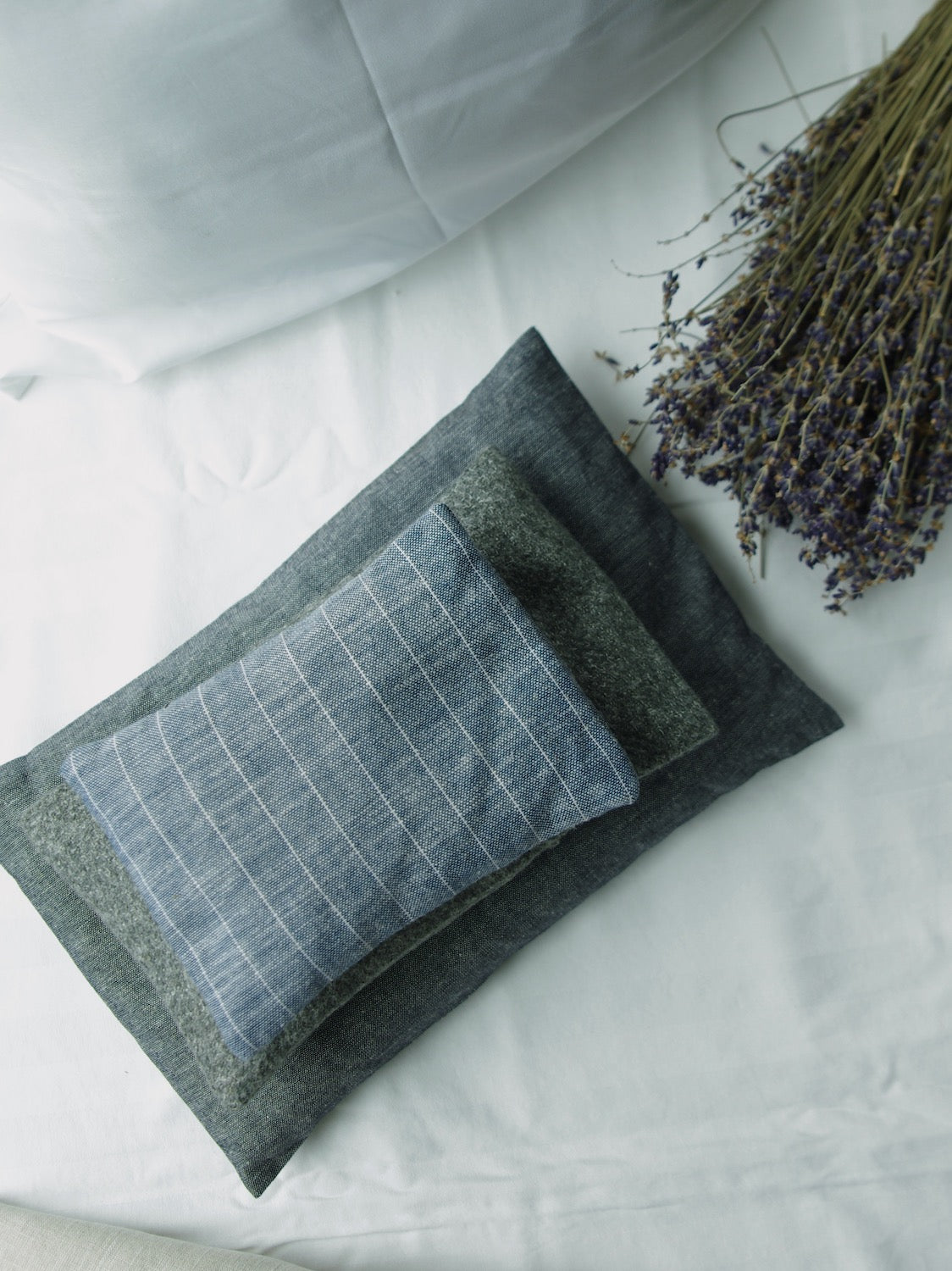 Lavender sachets made of dark linen next to bundle of dried lavender