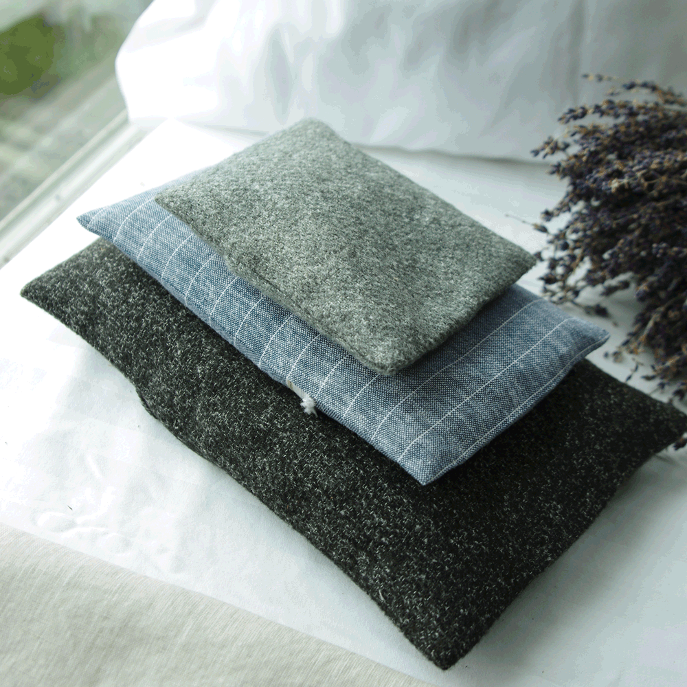 Stack of three linen lavender sachet pillows next to a bouquet of dried lavender.