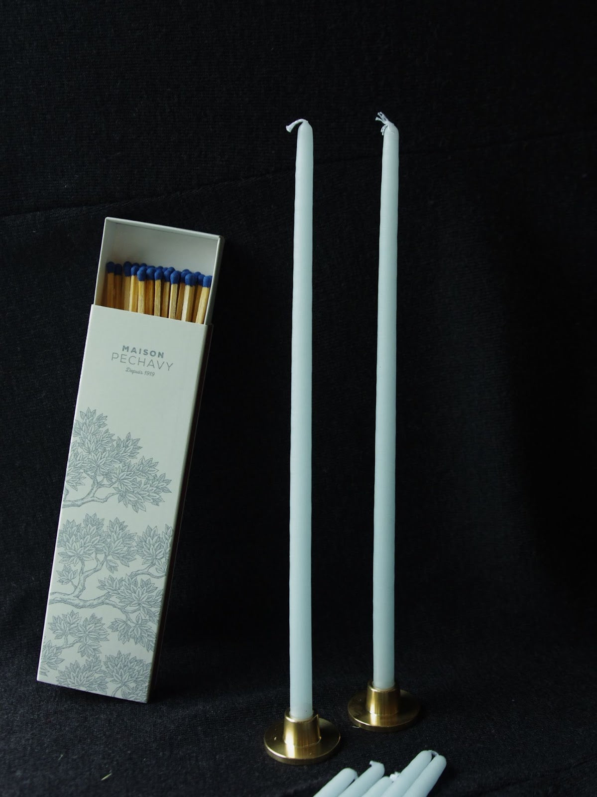 Maison pechavy light blue taper candles standing in gold candle holders next to long matches.