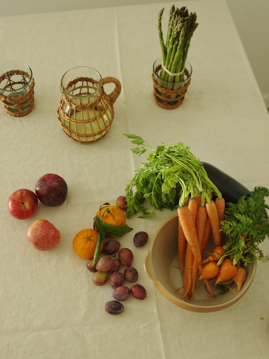 Rattan wrapped glassware sitting on table with fruits and vegetables