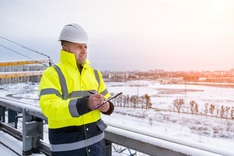 Site manager taking notes of construction site in snowy conditions