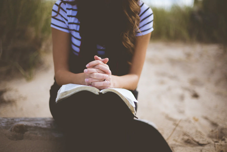 Woman praying with a bible outdoors
