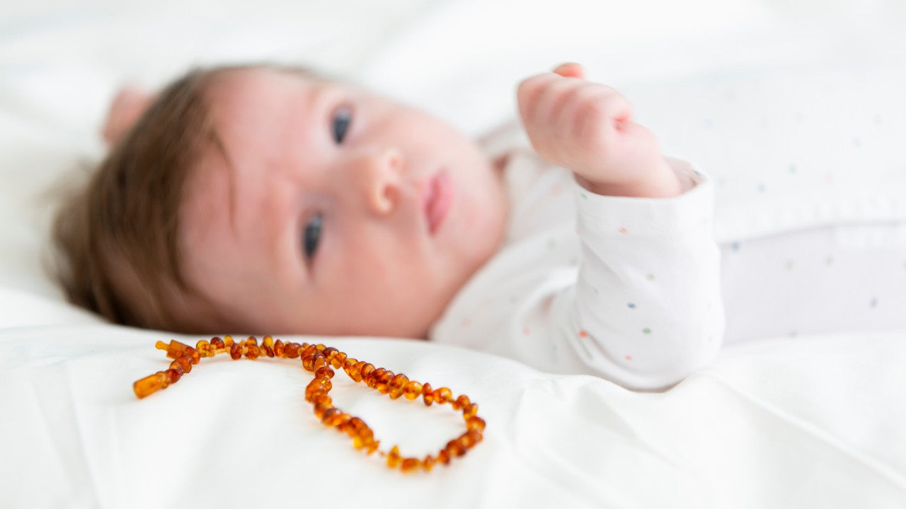 Amber Teething Necklace in Cognac Color and Baby on the Background