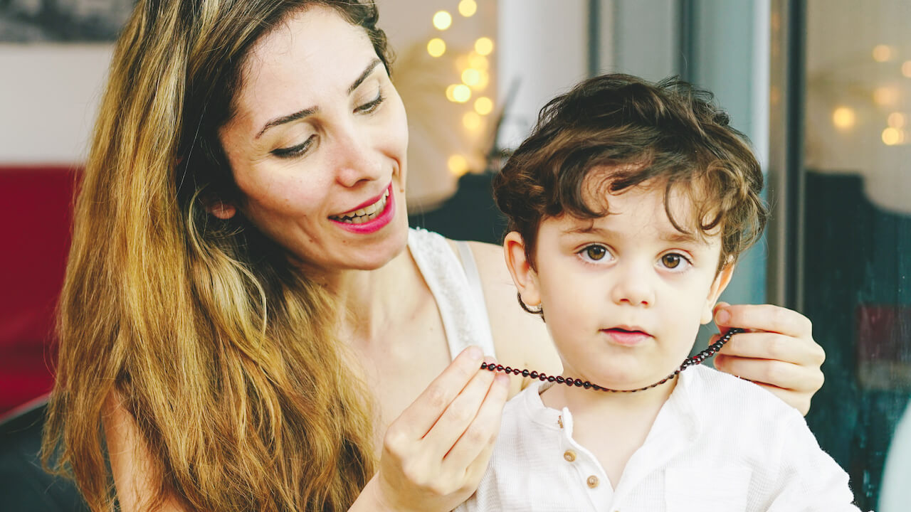 Mother Measuring Amber Guru Cherry Polished Baltic Amber Teething Necklace on Her Little One