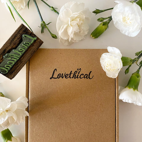 Image of Lovethical's packaging - a brown box with 'Lovethical' stamped on the front, and it is surrounded by white flowers.