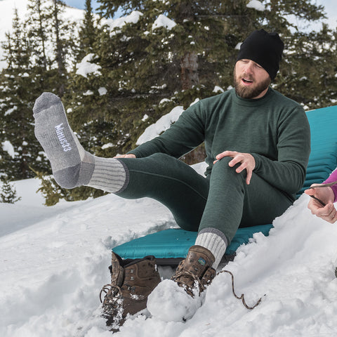 man sitting in the snow, wearing wool base layers