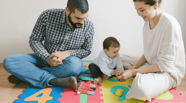 baby playing on puzzle mat with parents