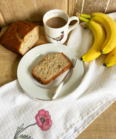 Banana bread recipe with a doodling lucy poppy flower tea towel and a bunch of bananas and doodling lucy mug