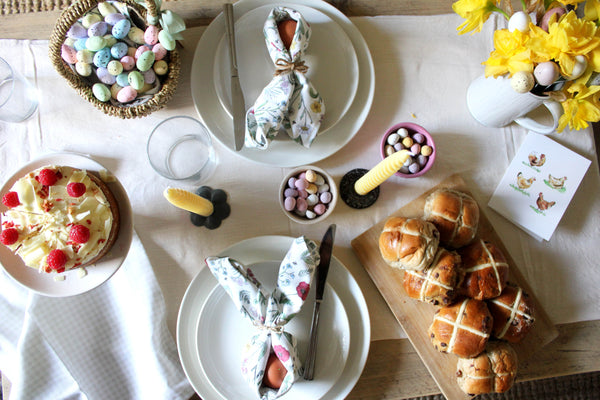 Easter table adorned with Doodling Lucy napkins, easter eggs, mini eggs and hotcross buns 