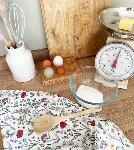 doodling lucy tea towel in a baking set up in a cotswold cottage kitchen, with scales, eggs butter and sugar