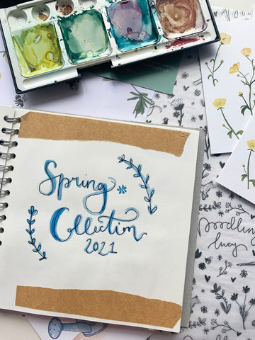 Spring collection sketchbook open on a table with paints