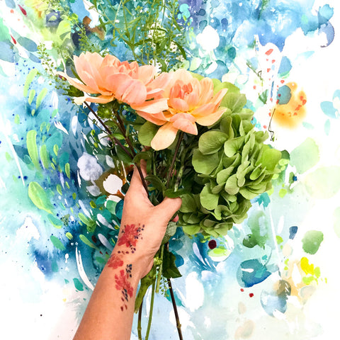Holding flowers with a floral tattoo and a turquoise painting by watercolour artist CreativeIngrid | Ingrid Sanchez.