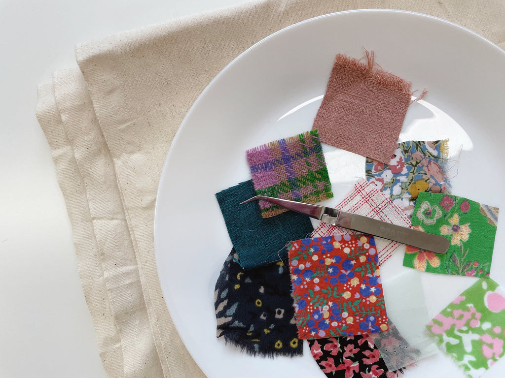 A dish filled with square swatches of different fabrics and tweezers