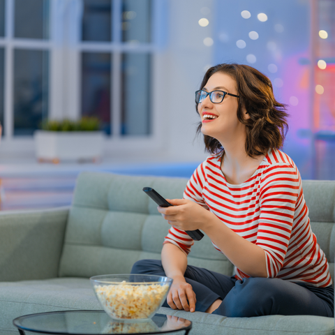picture of woman watching tv with popcorn on table and winter outside