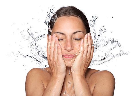 Woman splashing face with clear water