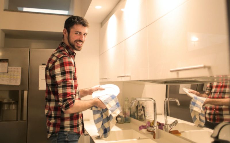 A man doing chores around the house to attempt to arouse his female partner