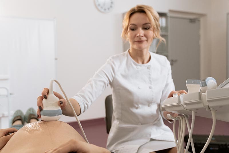 Healthcare professional administering ultra sound to pregnant patient