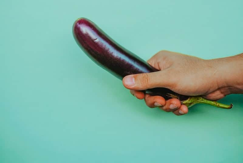 Man holding eggplant to suggest masturbation