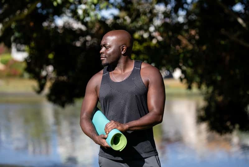 Man with yoga mat about to exercise to reduce bad cholesterol also uses nitric oxide boosters