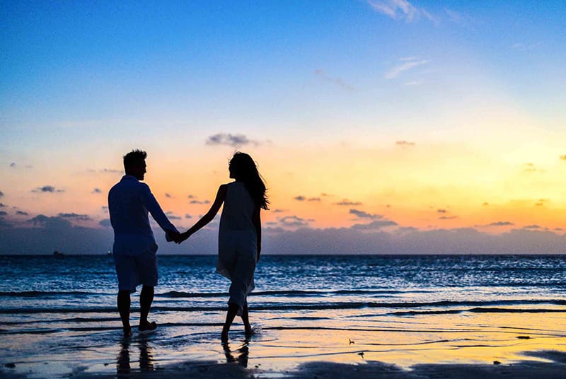 Sexually active couple walking on a beach at sunset