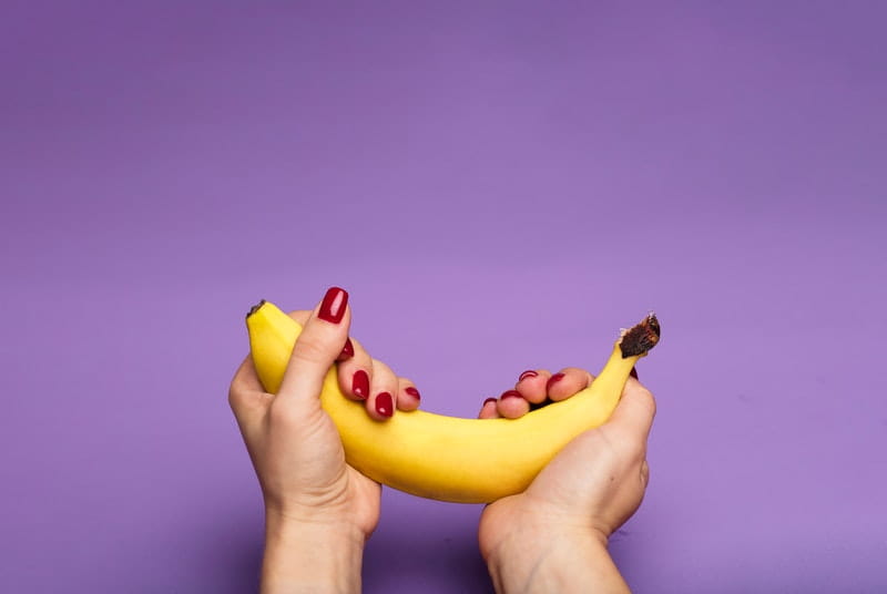 Woman gently cradling banana is if it were a penis