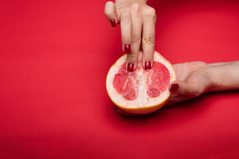 Yoni massage being demonstrated on a grapefruit half