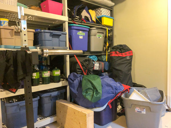 A messy pile of camping gear shoved near a shelving unit