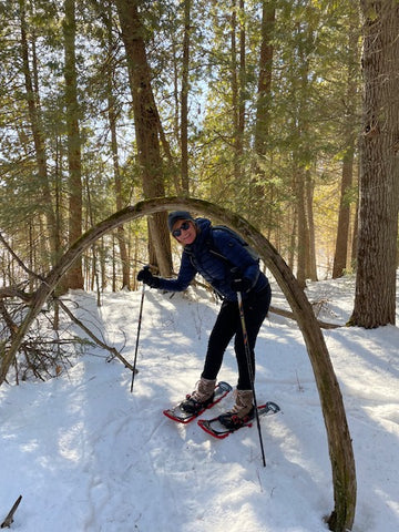 Joan Lawless poses by a bent tree while snowshoeing