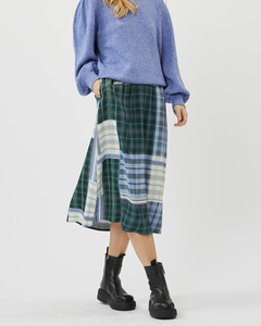 a model posing in the Minimum Women's Mola Midi Skirt in Impression paired with a blue sweater and black combat boots
