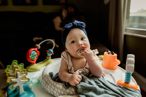 Infant girl with Ninni pacifier and toys in the living room