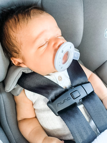 Baby sleeping peacefully in car seat with ninni pacifier