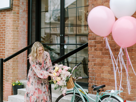 Amber stands next to a vintage bike with pink balloons outside of Pink Lemon Decor celebrating the opening of the curated home goods and vintage art prints store