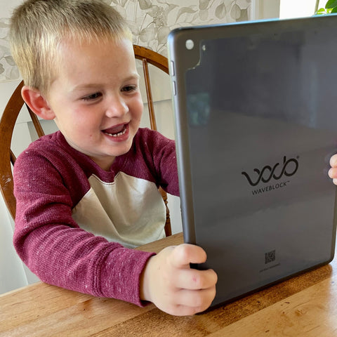 little boy using ipad with WaveBlock EMF protection sticker on the back of it