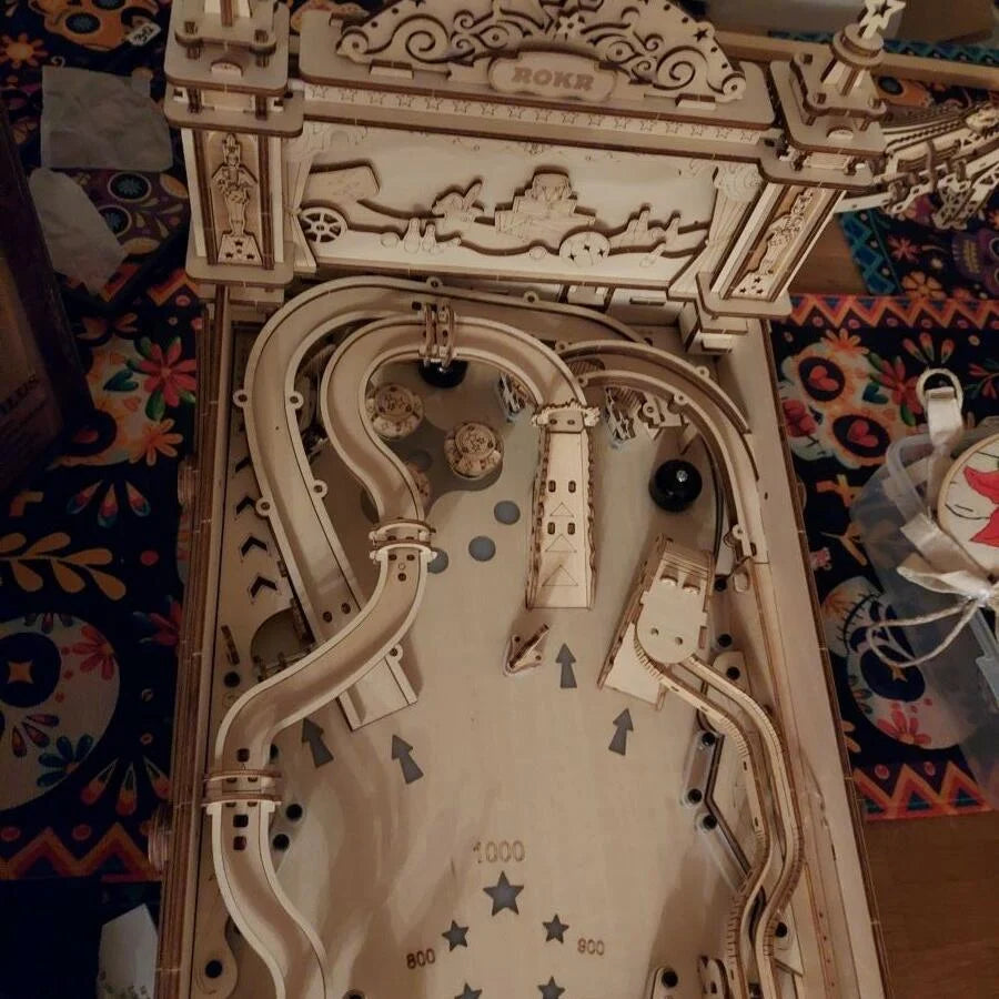 Intricate wooden pinball machine on a decorative table.
