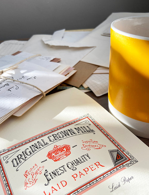 Piles of letters and writing paper with sunshine yellow mug