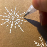 White gel pen snowflake design on kraft Christmas card