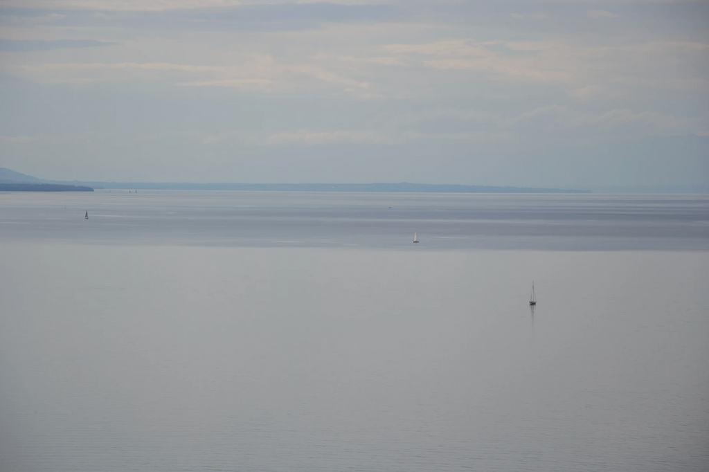 Foto von einem See, der sich bis zum Horizont erstreckt und mit den Wolken vermischt