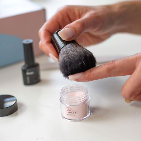 Excess dip powder is brushed off with a kabuki brush.