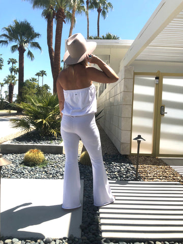 Downtown Betty showing the back of the Kundalini Whites Villa Onepiece in front of beautiful modern Palm Springs home with palm trees in the background