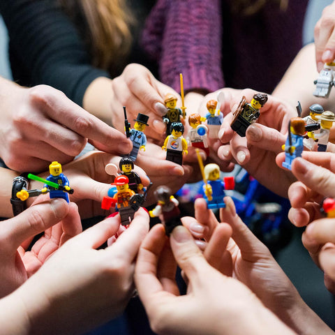 Different hands holding various Lego figurines