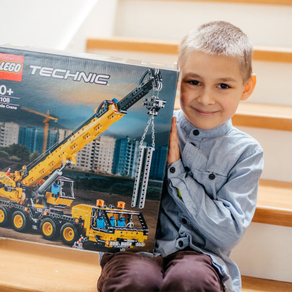 Happy young boy holding a LEGO® box
