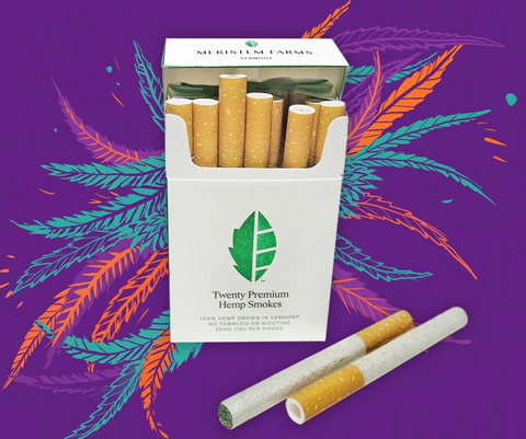 Purple background with white open pack of craft hemp smokes  with green lettering and green logo.  Orange and turquoise leaves pop out from behind the pack 