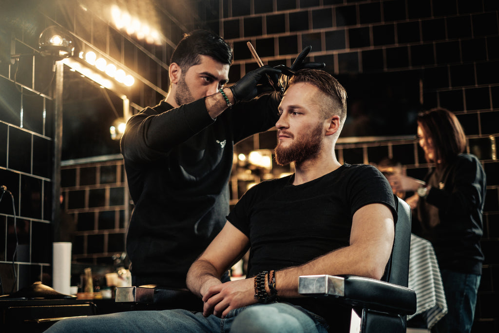 Un maître barbier coupant les cheveux dans un salon de coiffure