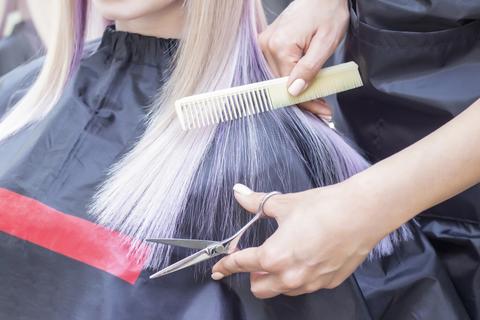 A hairdresser holding a pair of hair scissors with a comb