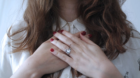 woman wearing silver-colored ring holding her chest