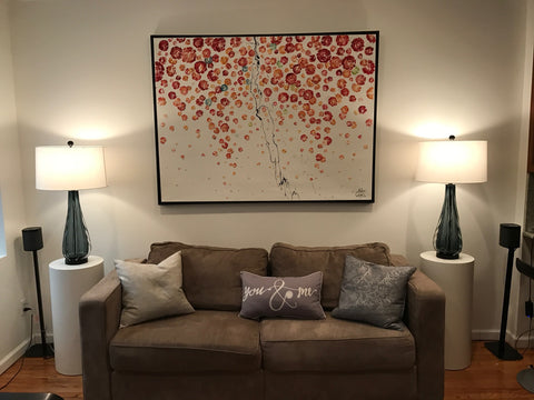 White laminate cylinder pedestals as lamp stands on either end of living room sofa.