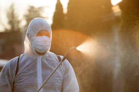 A person in PPE kit sanitizing the surroundings